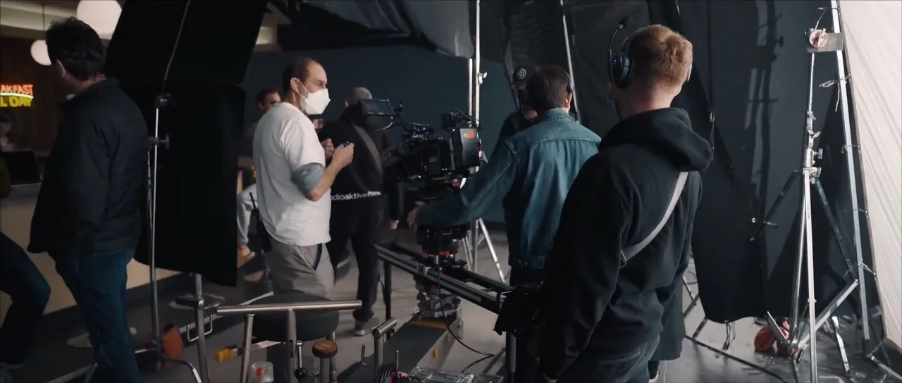 Camera crew filming on a set, with a camera on a rig and lights around them