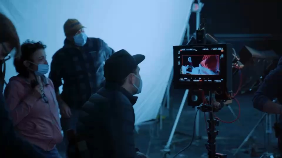 A director and crew watching a TV commercial take on a monitor during a night shoot